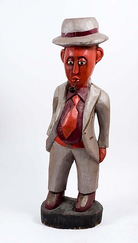 Holzskulptur. Man in Anzug mit Hut und Pfeife.